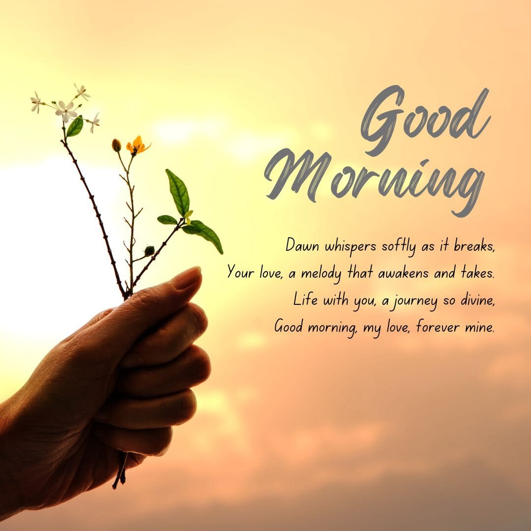 A hand holding a small branch with leaves and flowers against the backdrop of a sunrise. The image includes the text 'Good Morning' and 'Dawn whispers softly as it breaks, Your love, a melody that awakens and takes. Life with you, a journey so divine, Good morning, my love, forever mine,' making it perfect for good morning messages for wife image.